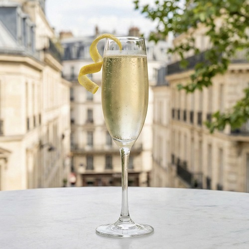 French 75 cocktail in a champagne flute with bubbly champagne, garnished with a lemon twist.